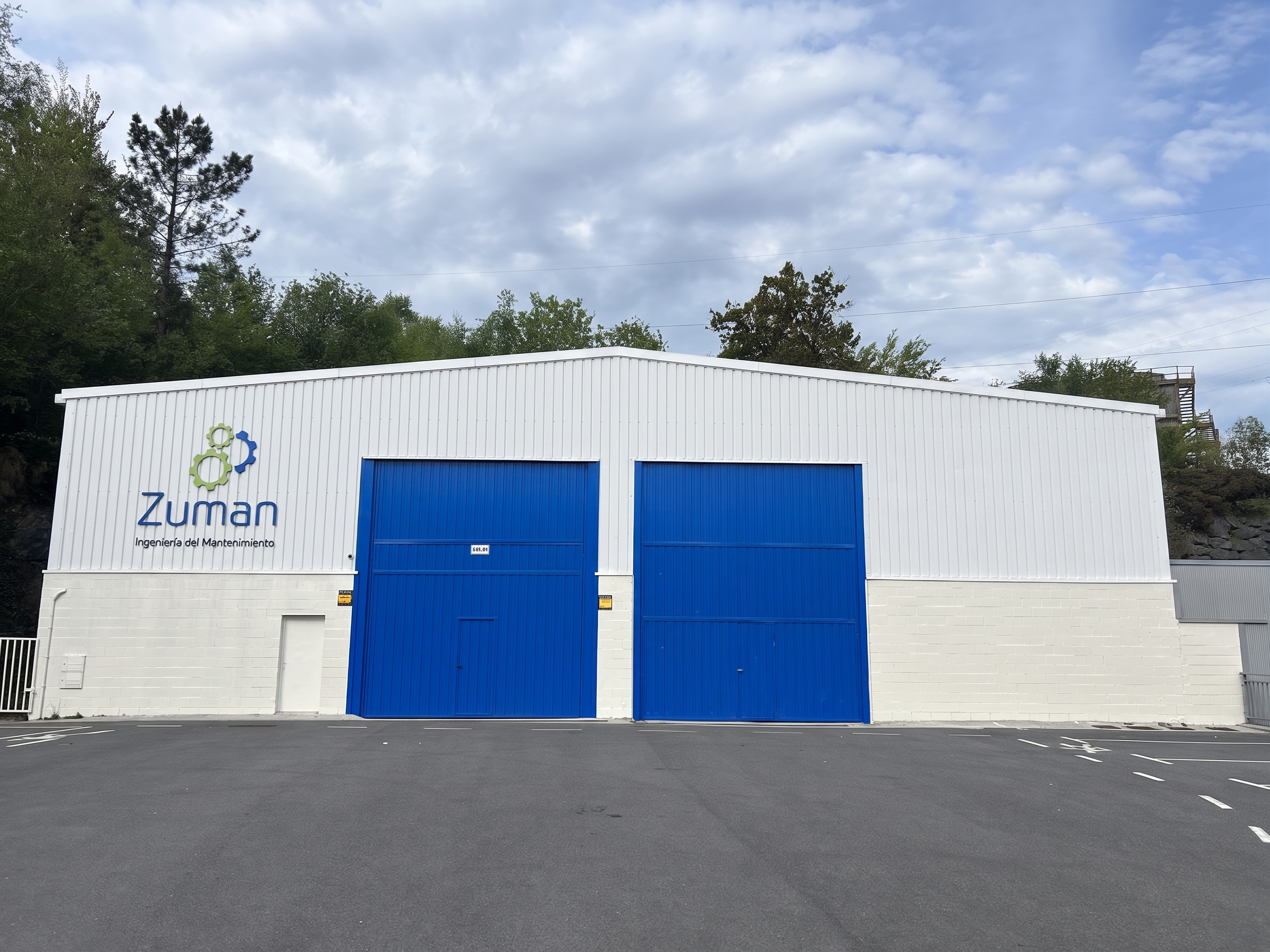 Pabellón propio de Zuman en Zumarraga, Gipuzkoa: nave industrial blanca recién pintada con el logotipo de Zuman y dos grandes portones azules